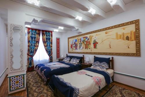 2 Betten in einem Zimmer mit Wandgemälde in der Unterkunft Goldenbukhara boutique hotel in Buxoro