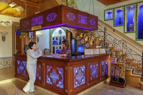 Ein Mann und eine Frau stehen an einem Tresen in einem Laden. in der Unterkunft Goldenbukhara boutique hotel in Buxoro