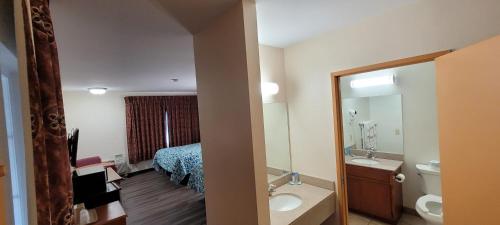 a bathroom with a bed and a sink and a mirror at Harvey's Motel SDSU La Mesa San Diego in San Diego