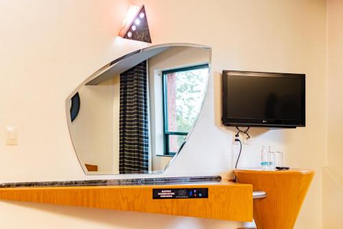 un espejo en una pared con una TV delante en Hotel Pasadena CDMX, en Ciudad de México