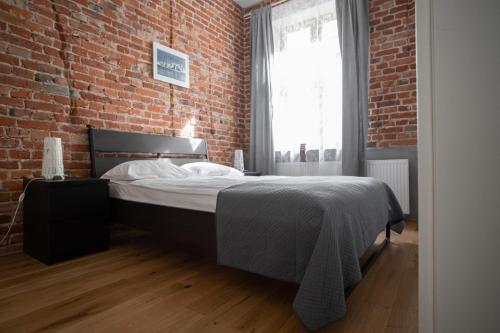 a bedroom with a bed and a brick wall at Apartament Fabrykanta by Good Time in Łódź