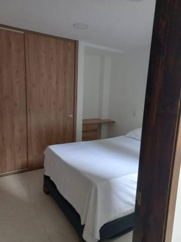 1 dormitorio con cama blanca y armario de madera en Acogedora Casa Circasia, en Circasia