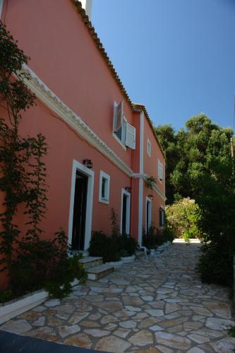 a red building with a stone pathway next to a building at Stavroula Studios in Paleokastritsa