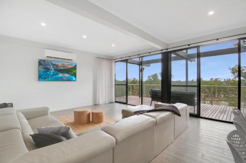 a living room with a white couch and glass windows at Warwilla Cliff Home in Paringa