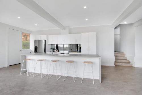 a kitchen with white cabinets and a counter with stools at Warwilla Cliff Home in Paringa