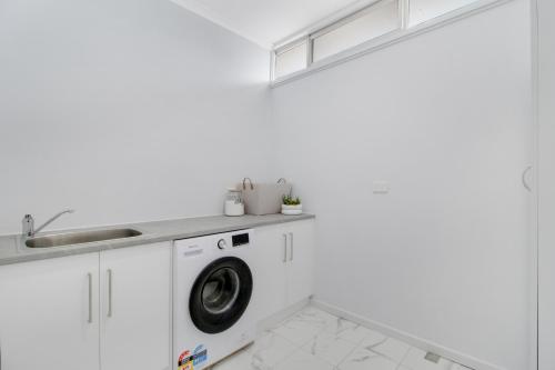 a white laundry room with a washing machine and a sink at Warwilla Cliff Home in Paringa