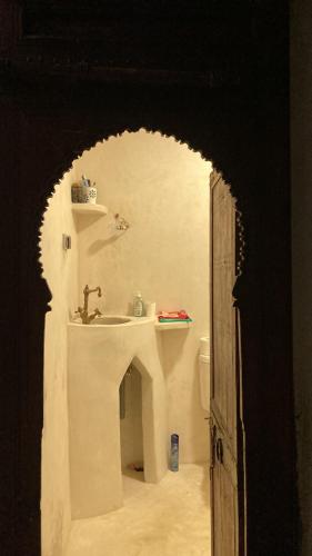 uma porta aberta para uma casa de banho com um lavatório em Riad mama Aicha em Asilah