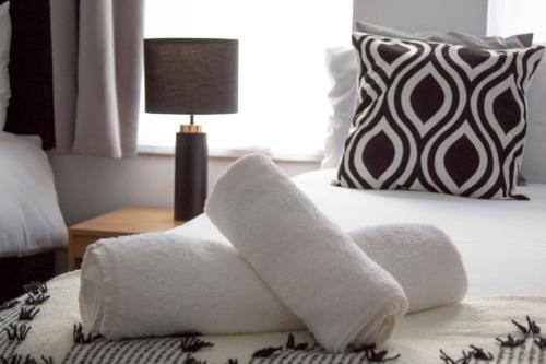a pile of towels on a bed with a lamp at SHM Stays HS2 workers Great for long term stays & Short Stays, 15 min drive to City Centre & Airport 2 min walk to Shops and Train Station in Birmingham