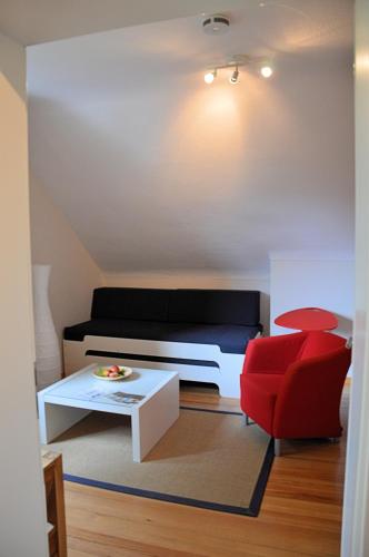 a living room with a couch and a red chair at Hotel Schlafschön in Hannoversch Münden