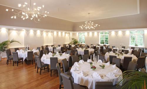 uma sala de banquetes com mesas e cadeiras brancas e um lustre em Hotel Schlafschön em Hannoversch Münden