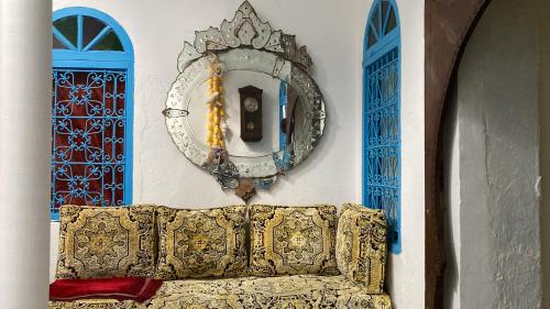 una camera con un divano e due finestre blu di Riad mama Aicha a Asilah