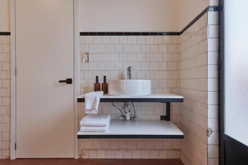 a bathroom with a sink and a white tile wall at Posada Independencia in Oaxaca City