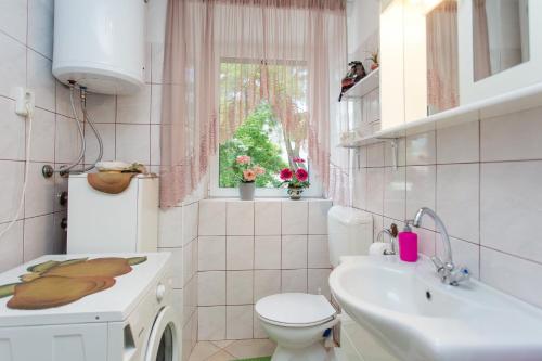 uma casa de banho com um lavatório, um WC e uma janela. em Apartments by the sea Kastel Kambelovac, Kastela - 20942 em Kaštela