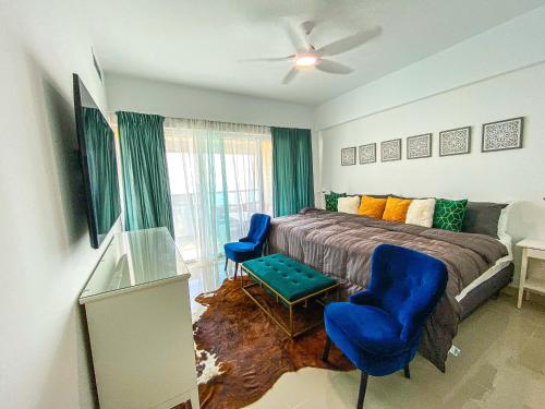 a bedroom with a bed and two blue chairs at JUAN DOLIO villa Palmera in Los Corrales