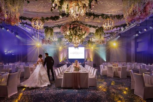a bride and groom walking down the aisle of a banquet hall at Clark Marriott Hotel in Clark