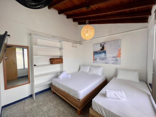 Hostal Casa Guadalupe في ميديلين: سريرين في غرفة بجدران بيضاء