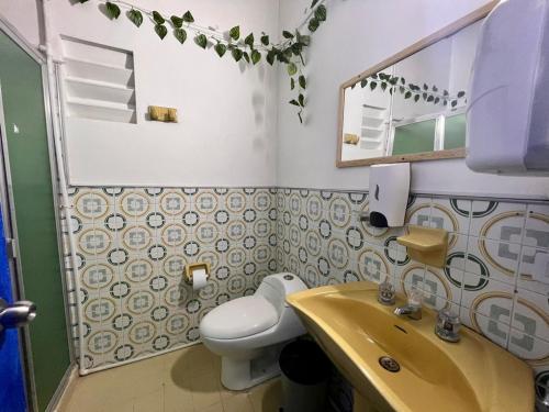 a bathroom with a sink and a toilet and a mirror at Hostal Casa Guadalupe in Medellín