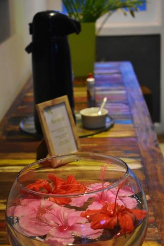 a glass bowl of flowers on a wooden table at Hibiscus Center in Búzios