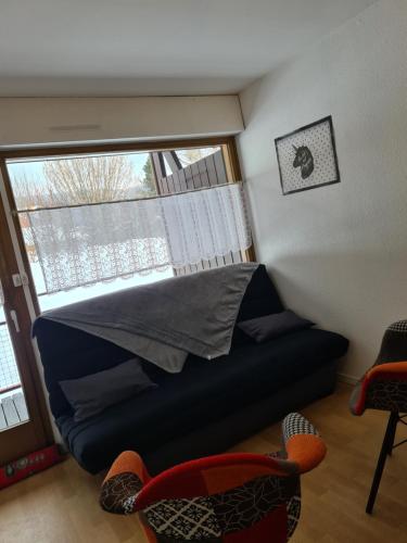 a bedroom with a couch and a large window at Studio à Xonrupt proche du Lac in Xonrupt-Longemer
