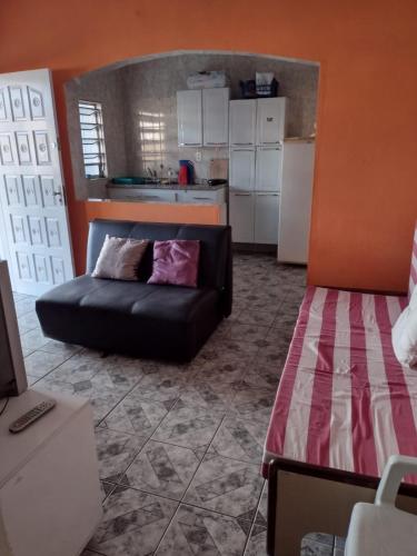 a living room with a black couch and a kitchen at Fala Mansa in Itanhaém