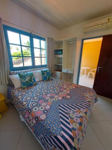 a bedroom with a large bed with a colorful blanket at Pousada Santo Aleixo in Porto De Galinhas
