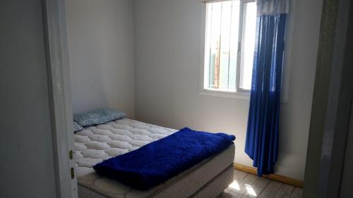 a bedroom with a bed with a blue blanket on it at Casa con piscina in Maipú