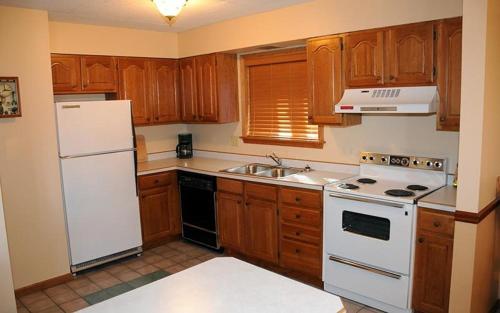 a kitchen with wooden cabinets and a white refrigerator at Seven Springs 2 Bedroom Standard Condo, Sleeps 10! condo in Champion
