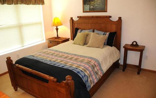 een slaapkamer met een houten bed, een lamp en een raam bij Seven Springs Woodridge 4 Bedroom Premium Condo, Mountain Views! condo in Champion