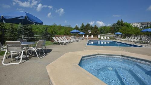 een zwembad met stoelen en een tafel en parasol bij Seven Springs Woodridge 4 Bedroom Premium Condo, Mountain Views! condo in Champion