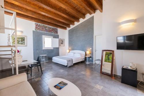 シラクーサにあるパラッツォ ジリストロのベッド、ソファ、テレビが備わる客室です。