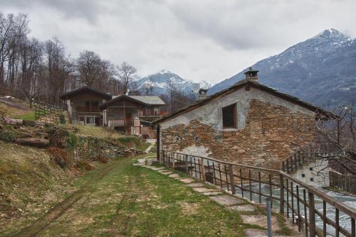 un vieux bâtiment en pierre sur une colline avec des montagnes en arrière-plan dans l'établissement Residence Joy Center, à Villar Pellice