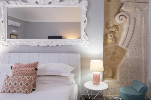 a bedroom with a white bed and a mirror at Palazzo Gilistro in Siracusa