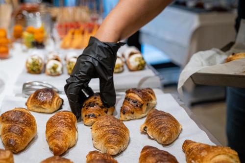 a person in latex gloves reaching for a tray of croissants at Palazzo Gilistro in Siracusa