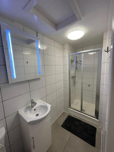 een witte badkamer met een wastafel en een douche bij Spacious, Modern 2 Bed Apartment in Londen