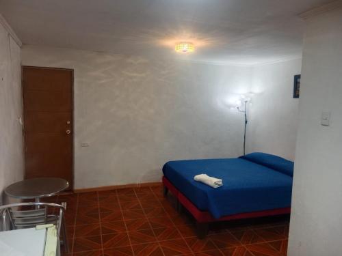 Un dormitorio con una cama azul y un taburete. en Habitación sol naciente peuco, en Calama