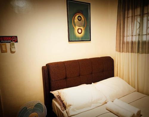 a bedroom with a bed with a headboard and a fan at One Oasis Condominium in Davao City