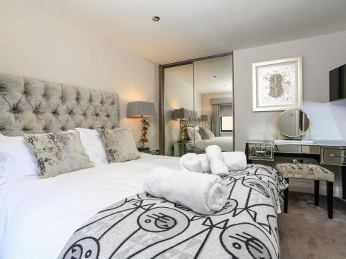 1 dormitorio con 1 cama blanca grande y espejo en Harbour Cottage, en Dartmouth