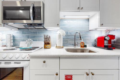 a white kitchen with a sink and a microwave at Julia Whitehead Guest Suites in Key West