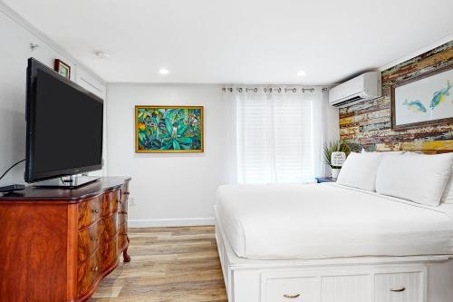 a bedroom with a bed and a flat screen tv at Julia Whitehead Guest Suites in Key West