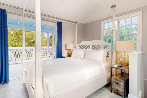 a white bedroom with a bed and windows at Julia Whitehead Guest Suites in Key West