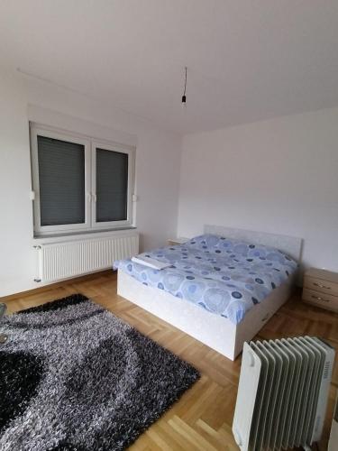 1 dormitorio con cama, ventana y alfombra en Delux Apartment, en Sarajevo