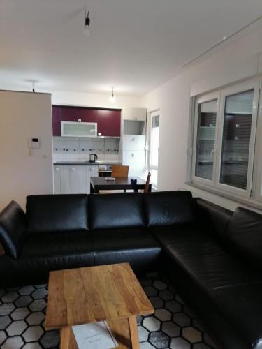 un salon avec un canapé en cuir noir et une table dans l'établissement Delux Apartment, à Sarajevo