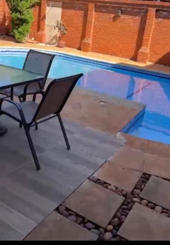 een tafel en stoelen naast een zwembad bij Casa hotel in Encarnación
