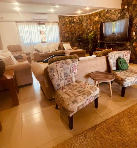 a living room with couches and chairs and a television at Casa hotel in Encarnación