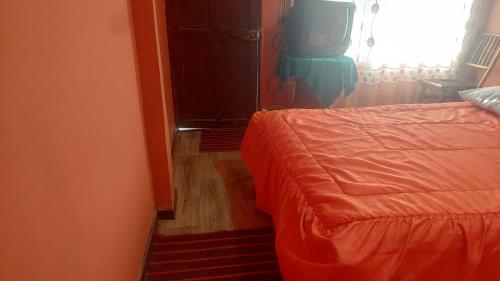 a bedroom with an orange bed and a television at Hostal Leyenda in Copacabana