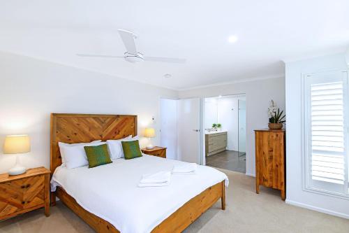 1 dormitorio con 1 cama blanca grande y baño en 10 Mona Vista Court en Coolum Beach