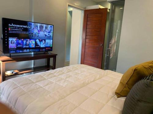 Schlafzimmer mit einem Bett und einem Flachbild-TV in der Unterkunft The Great Molave FAMILY ROOM in Cavite