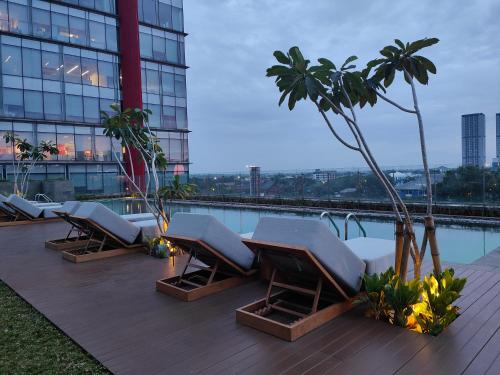 een rij ligstoelen op het dak van een gebouw bij Ra Suites Simatupang in Jakarta