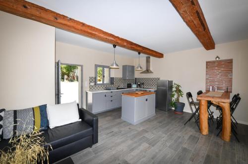 un salon avec un canapé et une cuisine dans l'établissement Les appartements du Mas Riols, à Saint-Cyprien