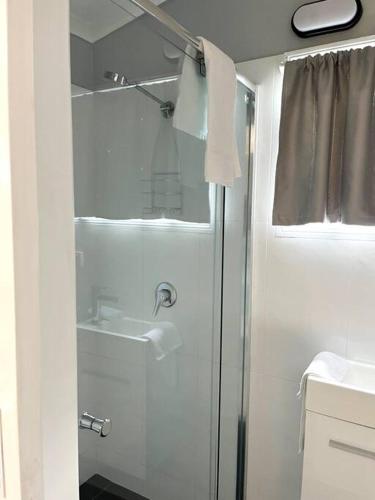 a white bathroom with a shower and a sink at Snapper Villa - Seaside in Urangan